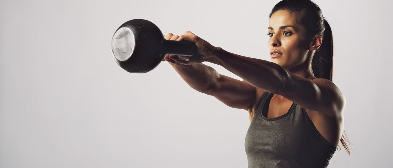 woman swinging kettlebell on a plain white background