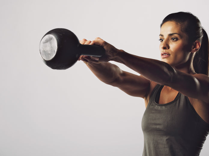 woman swinging kettlebell on a plain white background