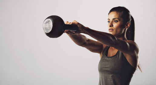 woman swinging kettlebell on a plain white background